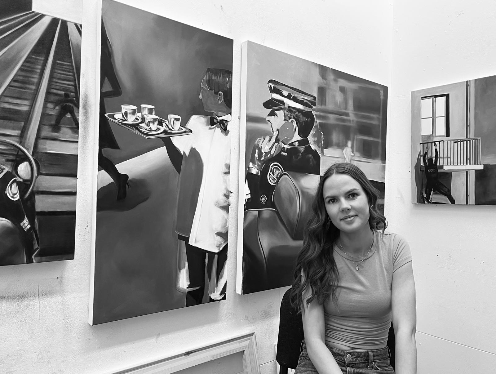 Louisa Murray sitting in front of her paintings.